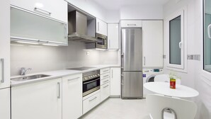 A modern kitchen with white cabinetry, stainless steel appliances, a built-in oven, and a refrigerator. - Prim Suite by FeelFree Rentals (San Sebastián)