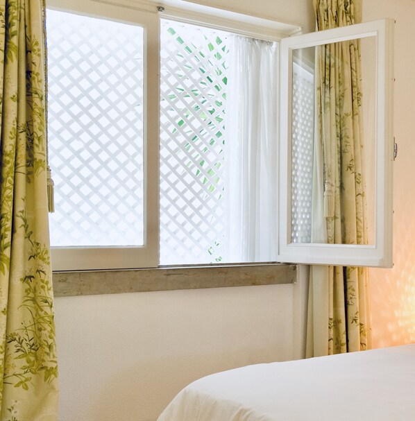 A room with a bed, a window with curtains, and a mirror.
