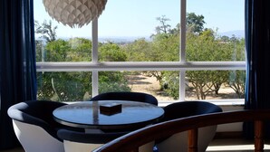 A room with a round table and two chairs, a hanging light fixture, and a view of trees and mountains through large windows. - Villa with 7 rooms, swimming pool, tennis court and garden (Alvor)