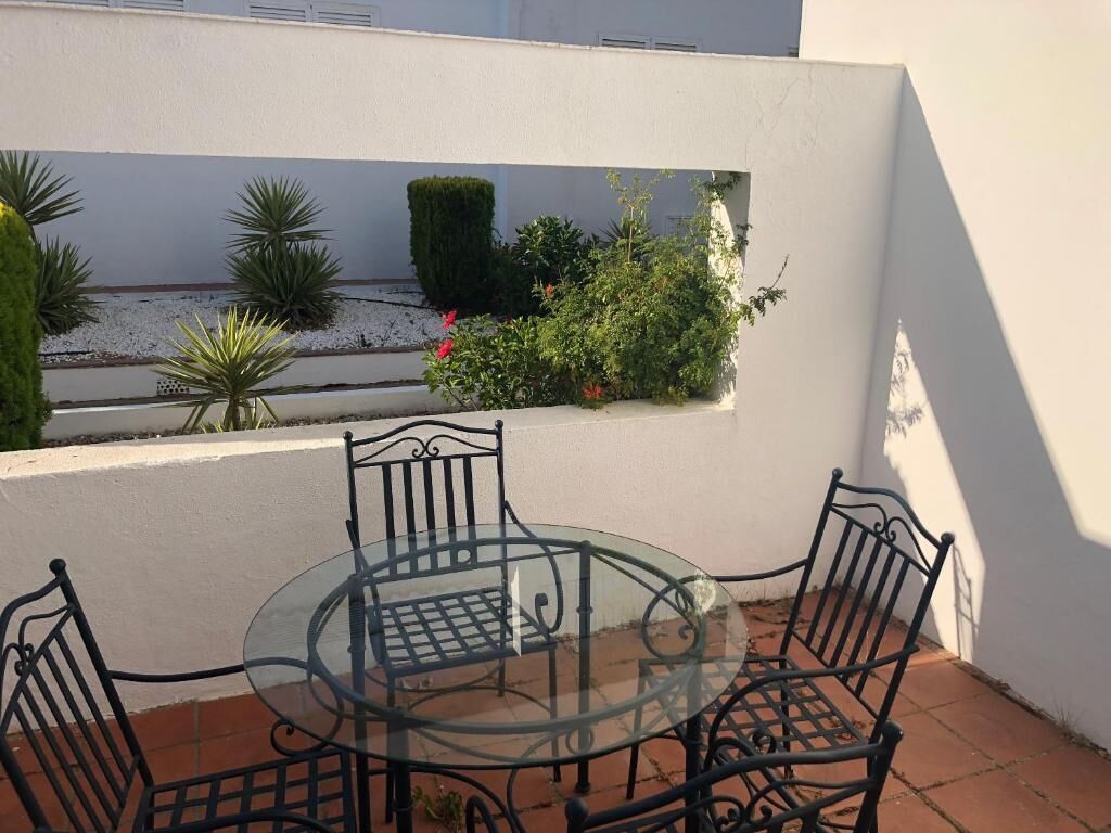 Et bord med glasplade og fire metalstole i et udendørs patio-område.