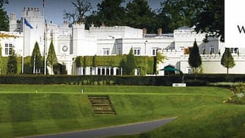 A large, white, castle-like building with a well-maintained lawn and a flagpole.