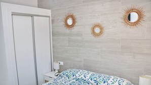 A bedroom with a bed, a nightstand, a mirror, and two wall-mounted sunburst mirrors. - Lovely rural villa with private pool (CONIL DE LA FRONTERA)