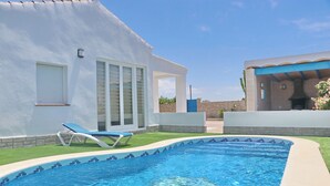 A swimming pool with a blue mosaic border, a lounge chair, and a white building with large windows and a door. - Lovely rural villa with private pool (CONIL DE LA FRONTERA)