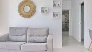 A modern living room with a grey sofa, a woven wall decoration, and three small shelves with potted plants. - Lovely rural villa with private pool (CONIL DE LA FRONTERA)
