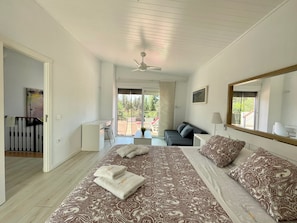 A bedroom with a large bed, a desk, and a balcony with outdoor furniture. - Chalet El Molino, with pool and chill-out (Chiclana de la Frontera)