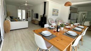 Um espaço de estar moderno com área de jantar, mobiliário branco e lareira.
