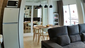 A modern kitchen with a microwave, refrigerator, and dining area with chairs and a table.