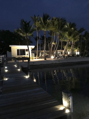 Enjoy a serene waterfront setting with a tranquil atmosphere, featuring a modern building with large windows and a dock extending into the calm water.