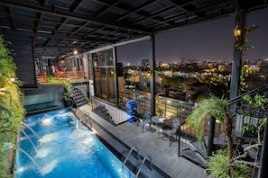 Una piscina en la azotea con vista a la ciudad, mobiliario exterior y un jacuzzi.