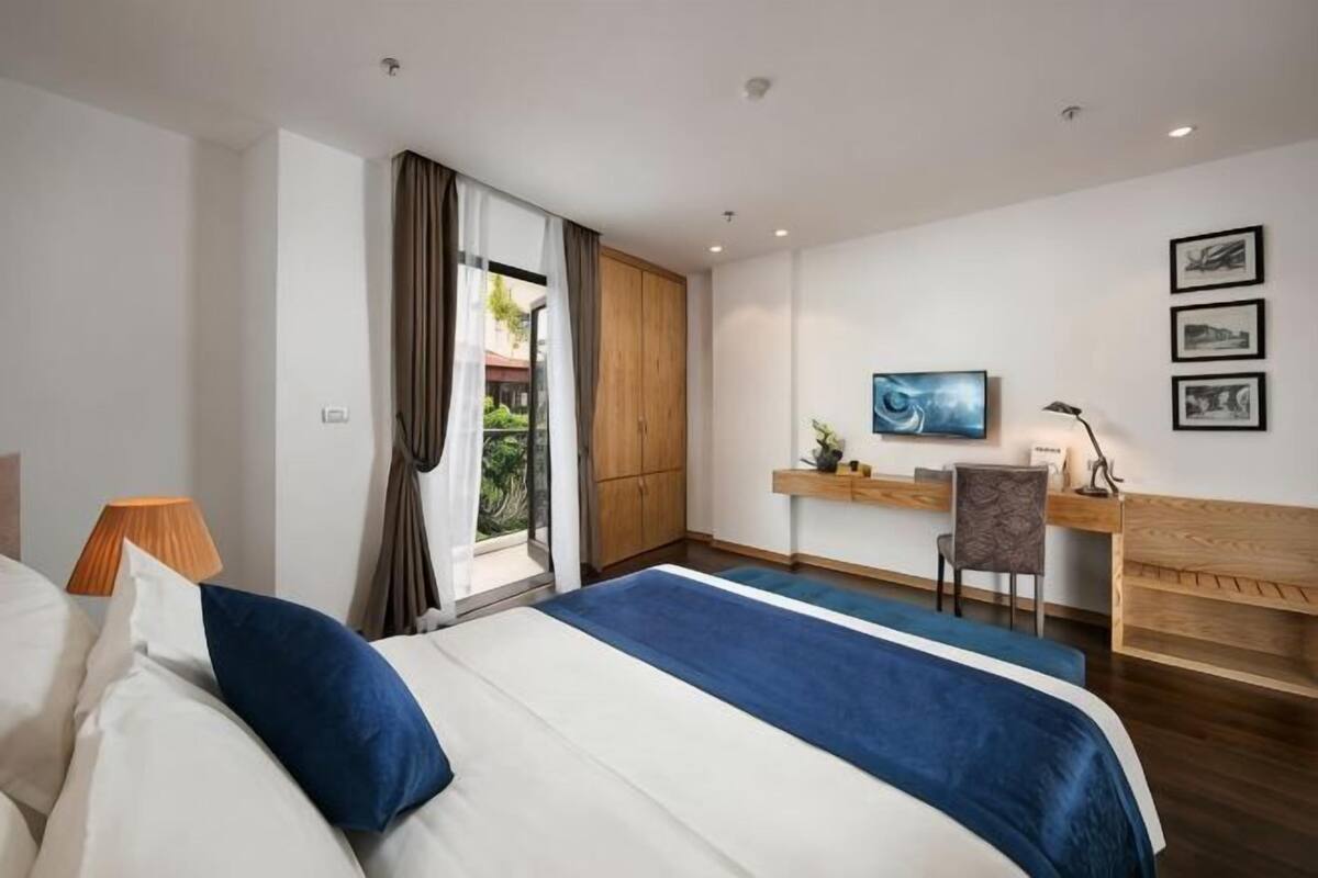 Una habitación de hotel con cama, escritorio, silla y vistas por la ventana.