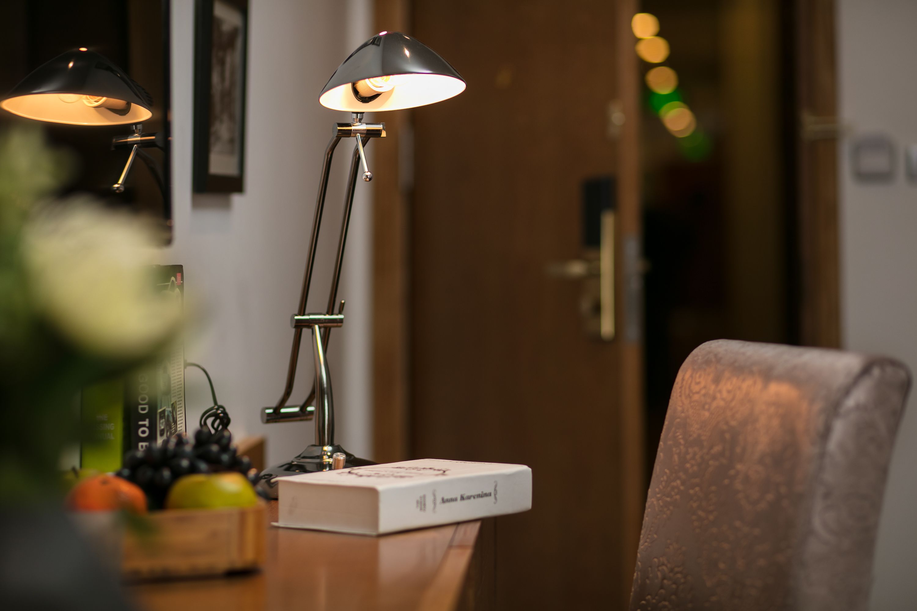 Una habitación con una lámpara de escritorio, una silla, un libro y un frutero.