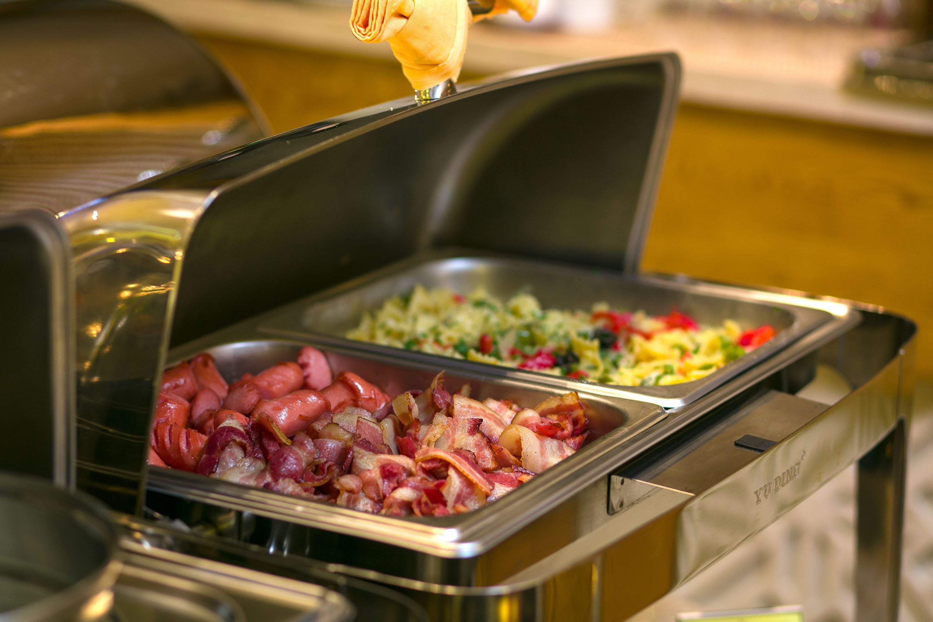 A buffet with various food options including bacon, vegetables, and a salad.