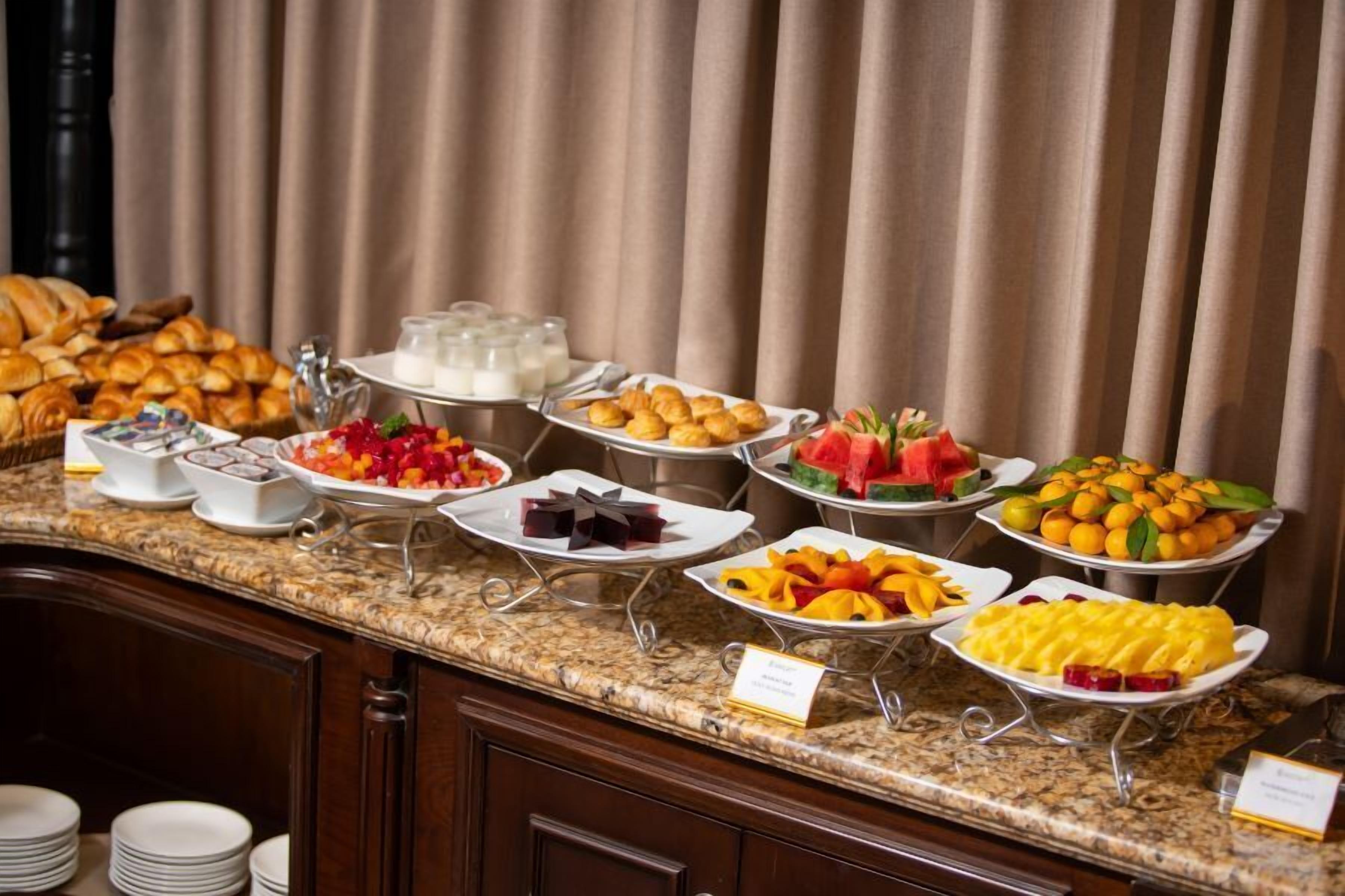 A buffet with various food items including pastries, fruits, and beverages.