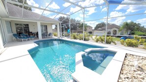 A swimming pool with a glass enclosure, lounge chairs, and a patio area. - Executive Home with Pool, Spa & Games Room minutes to Disney World (Davenport)
