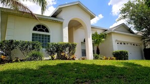 A two-story house with a white exterior, a large arched entrance, and a garage. - Executive Home with Pool, Spa & Games Room minutes to Disney World (Davenport)