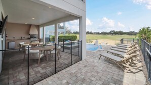 A modern outdoor patio with a dining area, a barbecue grill, and a pool.