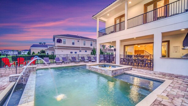 A swimming pool with a hot tub, lounge chairs, and a covered patio area.