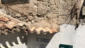 En smal gata med en vit byggnad som har en trädörr med texten ”EL PORTAL” och en grön skylt med bokstäverna ”Cr” och en symbol som föreställer ett hus.