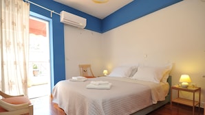 A bedroom with a bed, a chair, a nightstand, and an air conditioning unit. - Acropolis Home (Athens)