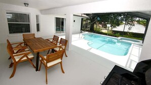 Un espace aménagé au bord de la piscine, avec une table et des chaises en bois, un jacuzzi et une vue sur le paysage environnant.