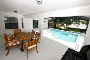 A poolside area with a wooden table and chairs, a hot tub, and a view of the surrounding landscape. - Updated 5BR Private Pool Home | Quiet Community | BBQ | Dog Friendly (Clermont)