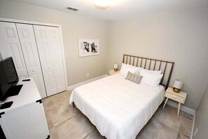 Une chambre à coucher comprenant un lit, des tables de chevet, un bureau, une télévision et une armoire.