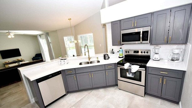 A modern kitchen with grey cabinets, a built-in oven, a microwave, and a dishwasher.