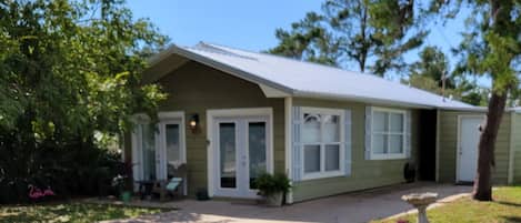 A single-story house with a front porch, a small garden, and a clear sky.