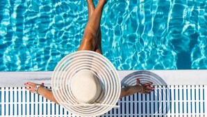 Una persona descansando en una piscina con un sombrero a rayas.