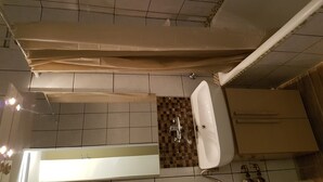 A bathroom with a tiled floor, a sink, and a bathtub.