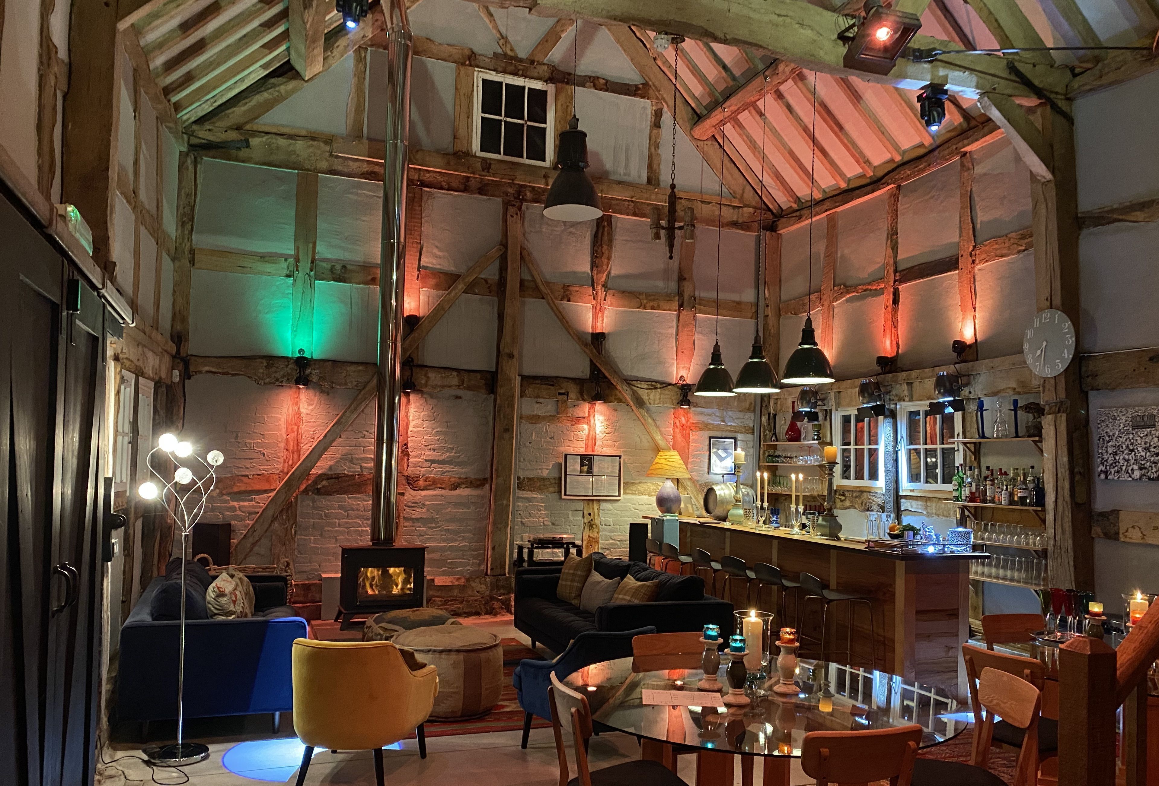 Un interior rústico con vigas de madera a la vista, una zona de bar, asientos y una chimenea.