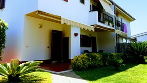 A two-story building with a balcony on the second floor, a covered entrance, and a small garden area with plants. - VILLA Mattia & Luca (Lido di Cincinnato - Anzio) (Anzio)