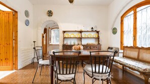 Ein Esszimmer mit Holztisch und -stühlen, einer Bank und einem Regal mit dekorativen Tellern.