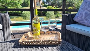 Ein Korbssessel mit Kissen, eine Flasche Miraflor Wein und zwei Gläser auf einem Tablett.