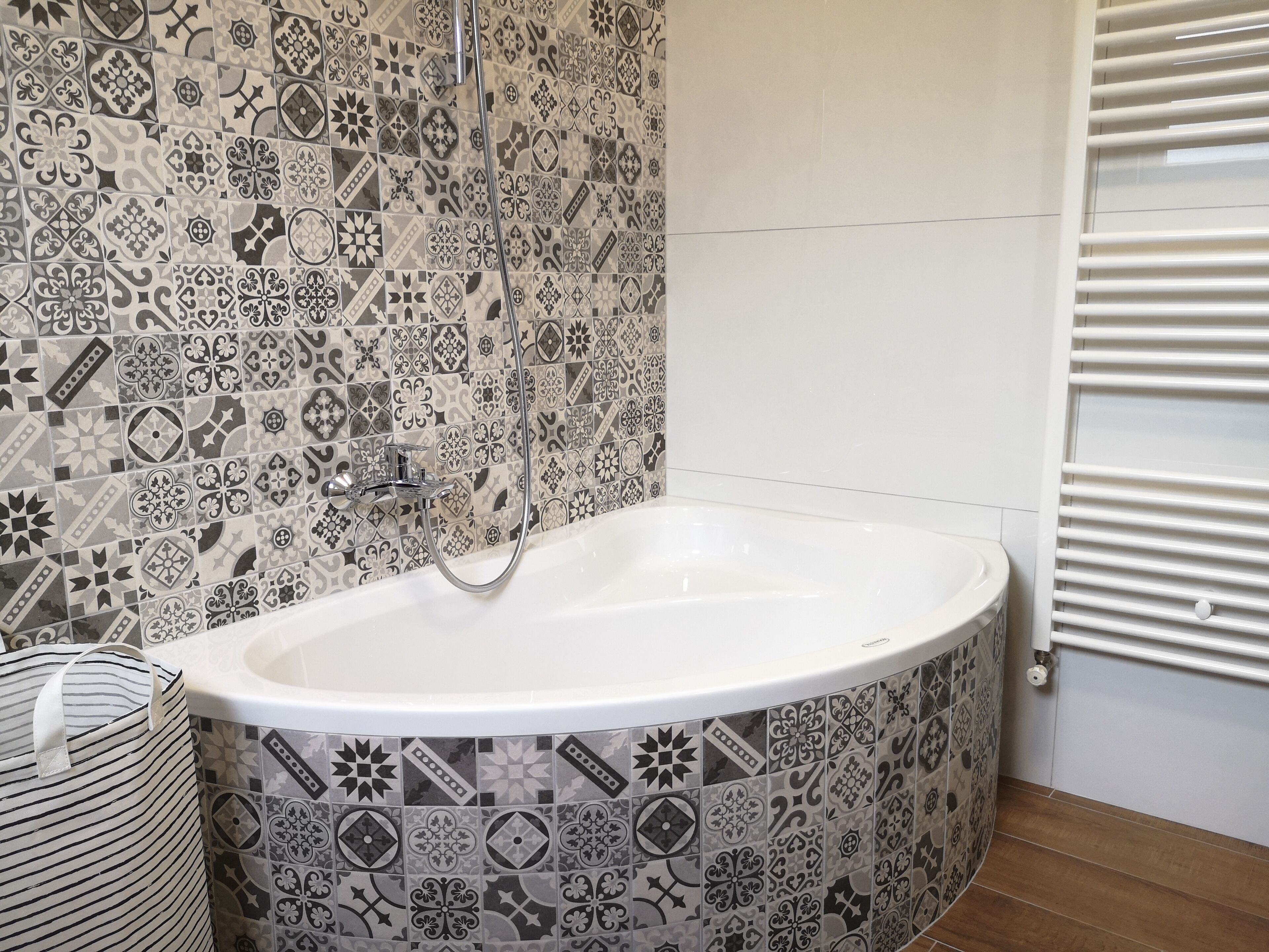 Et badeværelse med et fristående badekar, fliserede vægge og en radiator.