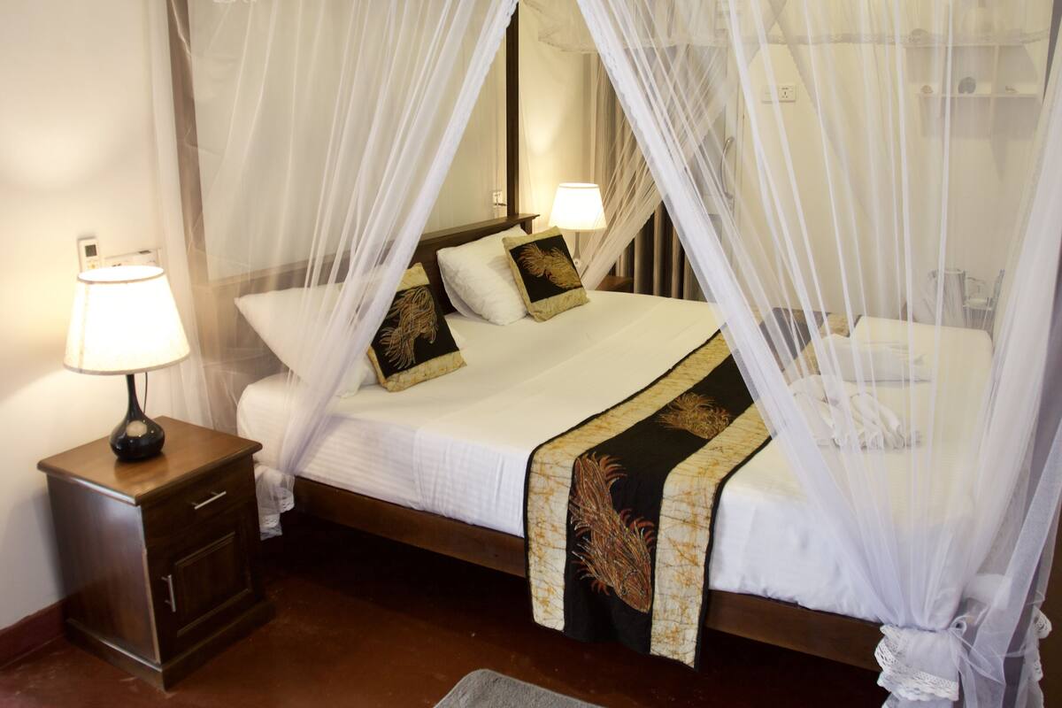 A bed with a canopy, a bedside table with a lamp, and a nightstand.