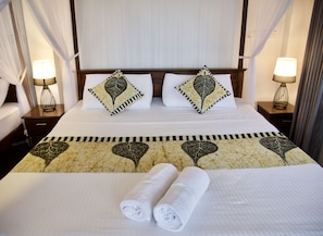 A neatly made bed with decorative pillows, a patterned bedspread, and rolled towels. - Glamour Mirissa (Mirissa)