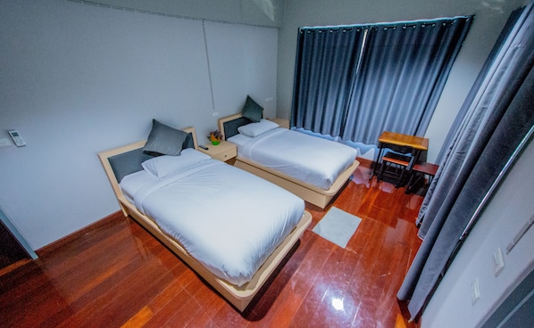 A room with two beds, a small table, and a curtain. - Na Siri Lakeview (Bang Phli)