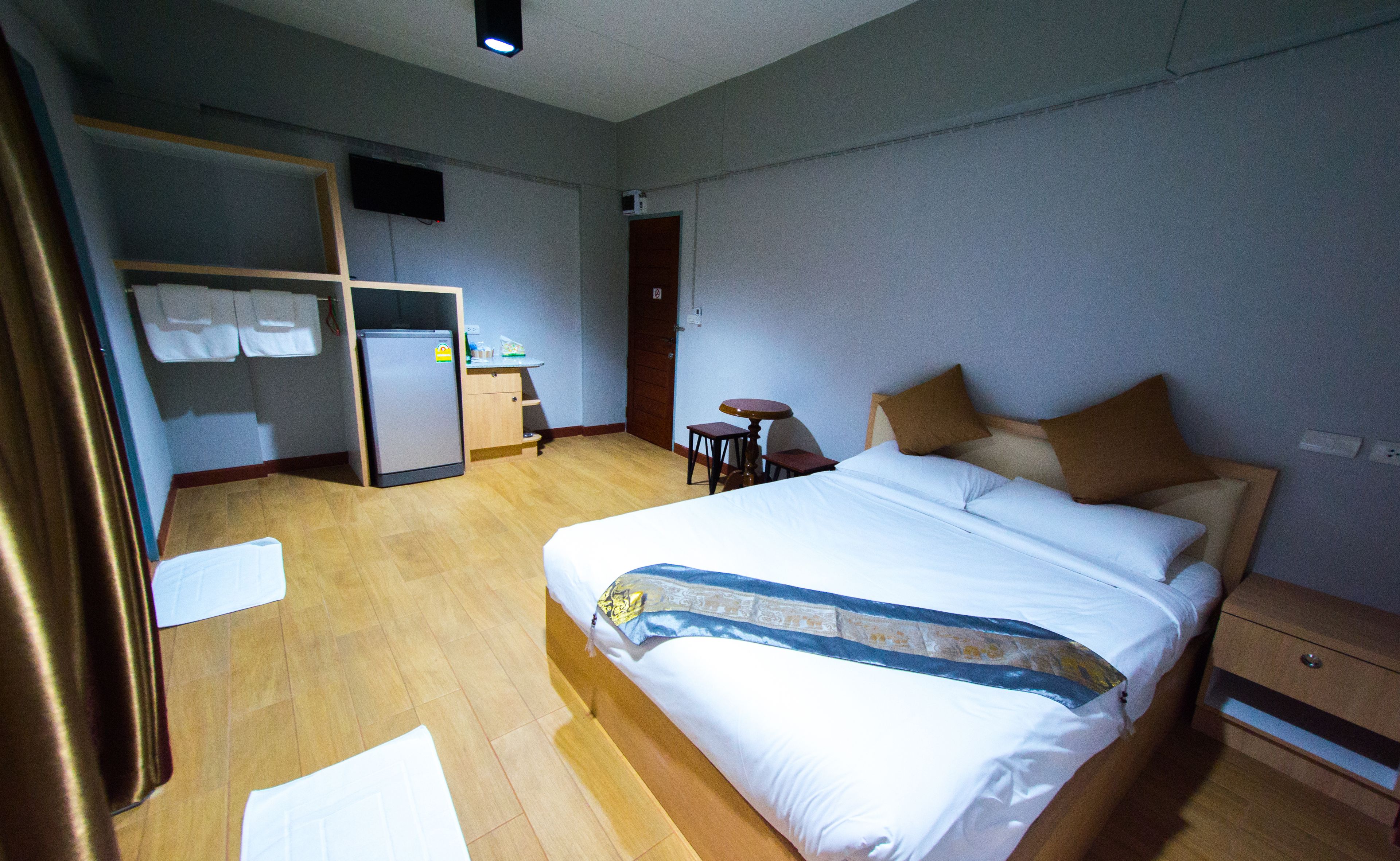 A hotel room with a bed, a desk, a chair, a wardrobe, and a television.