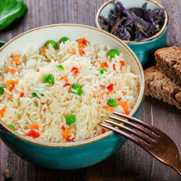 Un tazón de arroz con guisantes y zanahorias.