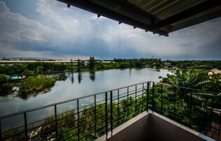 A balcony with a view of a calm lake, surrounded by greenery and a cloudy sky.