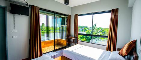 Habitación de hotel con dos camas, televisión, balcón con vistas y aire acondicionado.