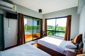 Une chambre d’hôtel avec deux lits, une télévision, un balcon avec vue et un appareil de climatisation.