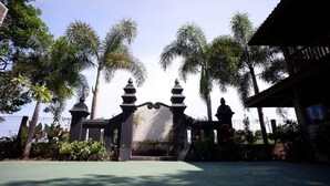 A traditional gate with a stone archway, surrounded by palm trees and a clear sky. - Griya Gendhis Saraswati (Klaten)