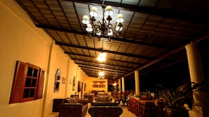 A spacious lounge area with patterned sofas, a chandelier, and a dining area with a red tablecloth. - Griya Gendhis Saraswati (Klaten)