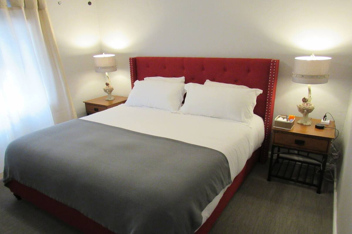 A hotel room with a large bed, two bedside tables, and a nightstand.