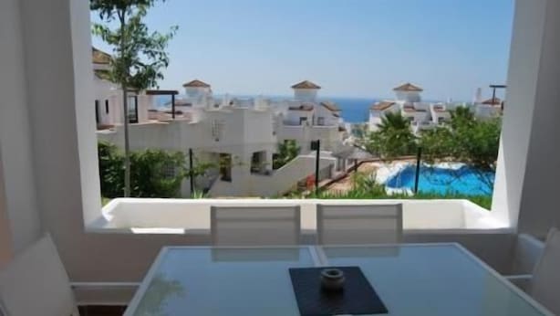 A balcony with a clear view of a coastal area, including buildings and a swimming pool.