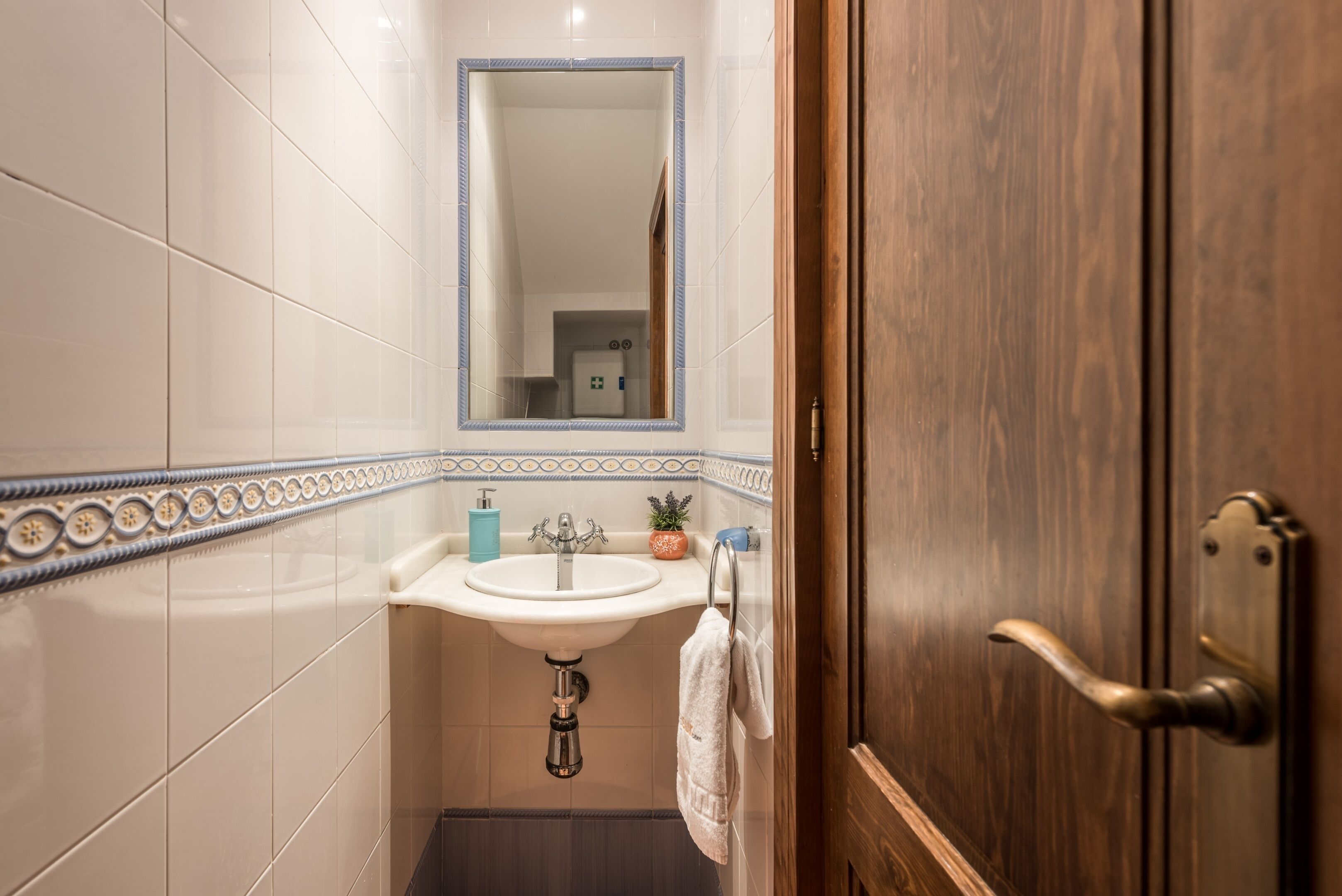 Baño con lavabo, espejo y puerta de madera.