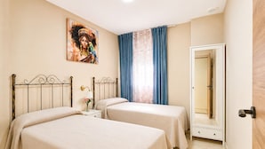A room with two beds, a painting on the wall, a mirror, and a window with curtains. - Centrally located apartment for 6,Tarifa (TARIFA)