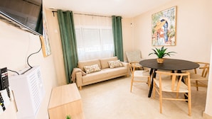 A living room with a sofa, a dining table with chairs, a TV, and a small table with a plant. - Centrally located apartment for 6,Tarifa (TARIFA)